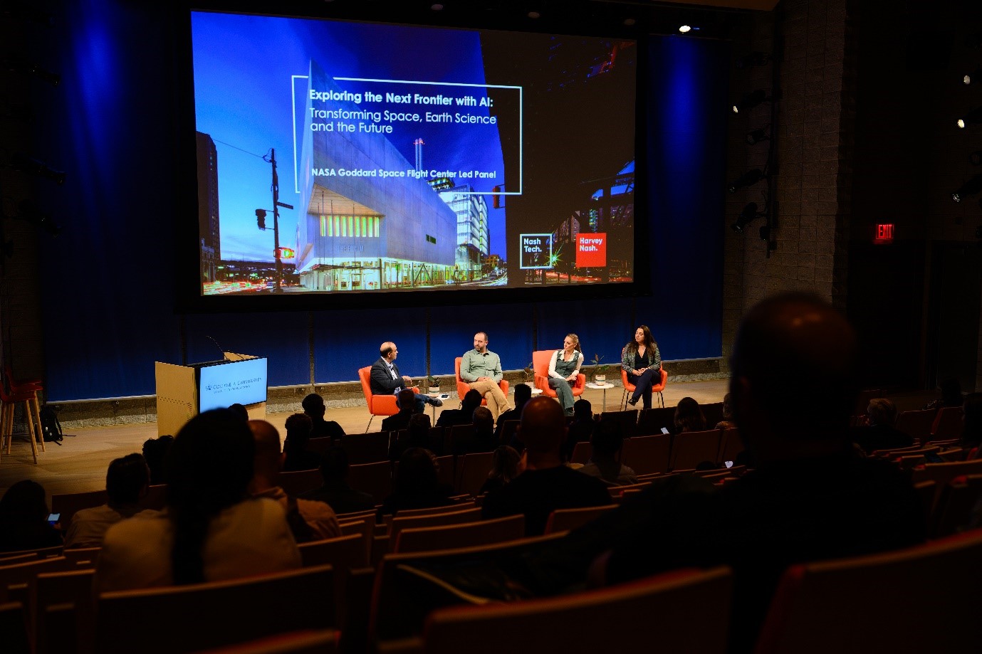 A group of people sitting in chairs in front of a large screenDescription automatically generated